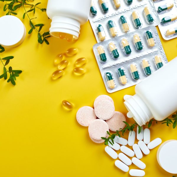 Flat lay of pills, fish oil, vitamins on yellow background, Healthcare concept, healthy food, supplements for healthy good life, Immune booster.