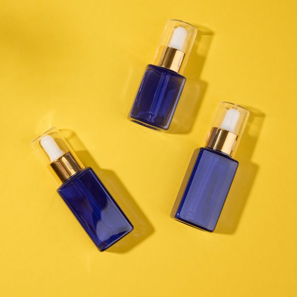 glass cosmetic blue bottles with a pipette on a yellow background. Cosmetics SPA branding mockup, top view, copy space