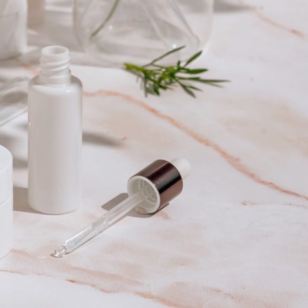 Natural cosmetic products in white packaging with laboratory glassware. Science and skincare concept Natural cosmetic products in white packaging with laboratory glassware. Science and skincare concept Compositions with cosmetic packaging in a medical style and plant shadows. Front view, selective focus